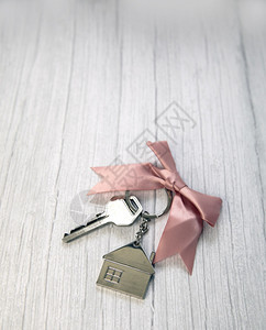 新房银钥匙带小子顶视图钥匙链带复制空间和白色木质背景文本空间银房新钥匙为了礼物贷款图片