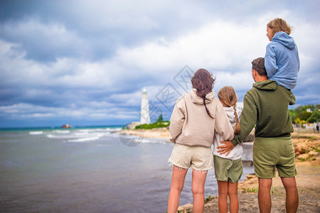 幸福4个家庭四口近风暴海岸附看着灯塔四口步行到灯塔云景观图片