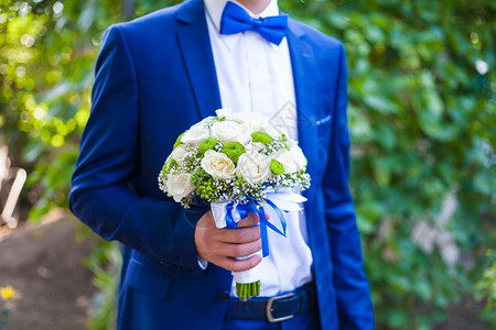 美丽的婚礼花束放在新郎手中领带统一已婚图片