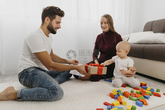 快乐父母给孩子送礼物的家庭婴儿沙发图片