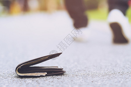 麻烦青年男子丢失了皮钱包在街头徒步人行道上的钱财在旅行途中钱袋紧贴地落在路混水泥的人行上钱包具体男人图片