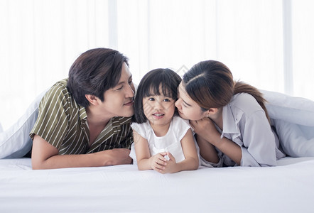 亚洲人可爱的家庭在节假日过着快乐的时光在家一起玩白床上的在室内时间图片