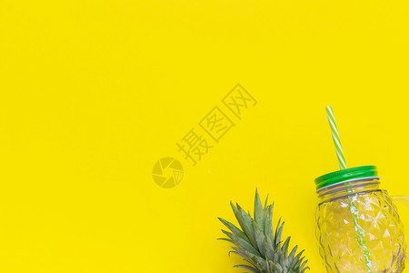 带有绿叶菠萝和稻草的空玻璃罐用于黄色背景的水果或蔬菜冰沙鸡尾酒和其他饮料顶视图复制空间模板带有绿叶菠萝和稻草的空玻璃罐用于黄色背图片