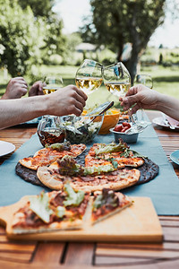 喝一种人们朋友在夏季野餐室外晚宴期间在一家庭花园里做吐司朋友在一家庭花园里做吐司在夏日野餐室外晚宴中朋友在后院果园里的一个用披萨图片