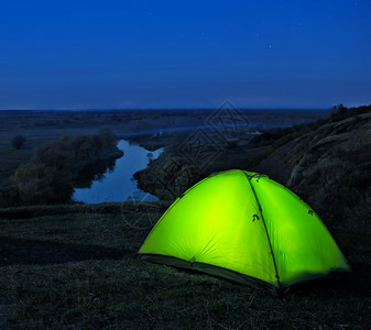 绿色帐篷里开灯在河上山边图片