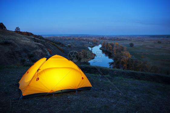 冒险水自由隐私和旅行的概念在河上一座山的橙色帐篷里照亮了在河上一座山的个橘色帐篷里照亮了点图片