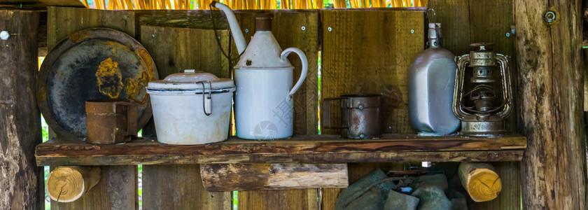 家庭木制架子上的旧餐具一些生锈的旧杯和板块历史原始设备木制的灯图片