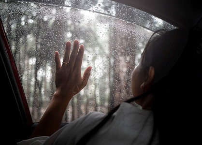 情怀年轻的观看孤单地坐着悲伤的年轻女人在雨天车里想起她的情人图片