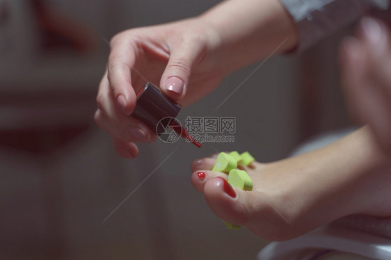 女制作手头上的侧面视图在脚指甲上涂凝胶拉克Gellac身份不明的妇女在家脚上修用指甲涂画Gellac侧面观点有选择焦点黑房美观概图片