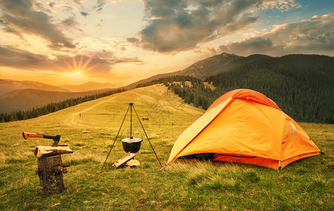 橙色帐篷停在山坡附近的平原上图片