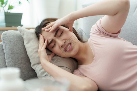 女士生病的年轻因偏头痛健康与疾病概念而头痛在沙发上睡家中觉年轻女因偏头痛健康与疾病而头痛亚洲图片