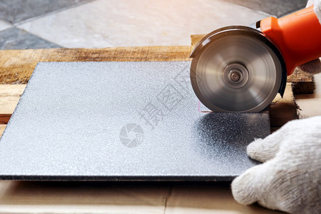 身着白布手套的建筑工人正在用电磨机切割瓷砖并使用电磨机具体的危险地点图片