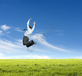 生态蓝色的男快乐年轻人在晴天背景下草地上跳跃图片