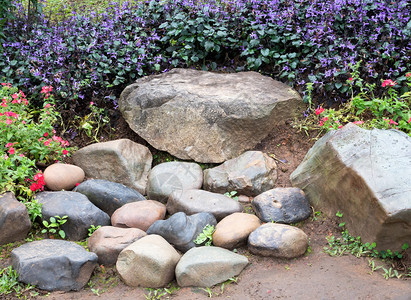 季节春天植物园旅行者在花朵中坐的石头座椅花园图片