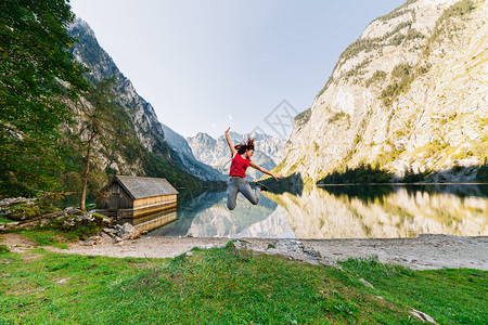 旅行景观年轻女子在山下湖边的码头上跳跃徒步旅行图片