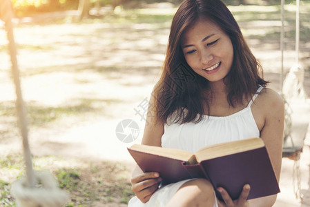健康自由年轻美女在公园里看书时笑脸微的表情学生图片