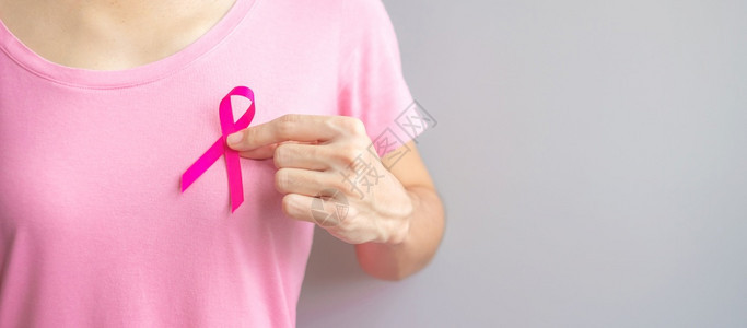 穿粉红T恤的妇女手握粉丝带特写背景图片