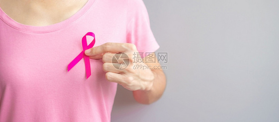 穿粉红T恤的妇女手握粉丝带特写图片