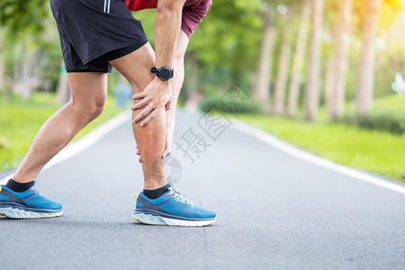 清晨跑步时感到肌肉疼痛的男青年图片