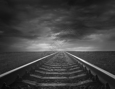 孤独黑白图像铁轨进入黑暗的天空风景黑色和白图像与铁轨相距不远的阴暗天际图象灰色的路图片