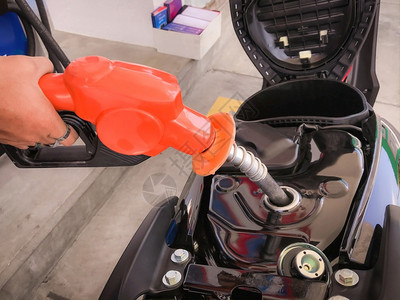 笔芯泵紧闭持有燃料撒油机的雇员手并将苯基燃料添加到摩托车配额燃料罐中加油图片