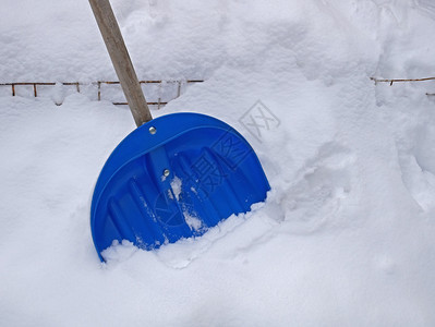 外部季节大蓝塑料铲用来除雪站在一个大地上紧闭深的图片