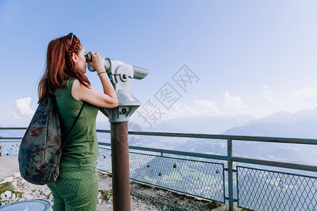 德国海滩参观在Coin经营的Binocolus观光旅行者中看山丘和日落的年轻红发女青图片