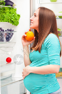 家绿色饮食孕妇在冰箱前的照片来自图片
