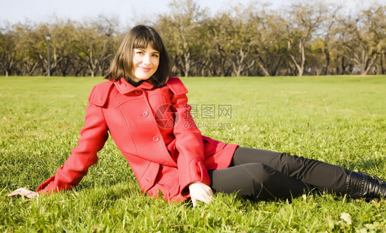 坐在绿草上的年轻女微笑孩外套图片