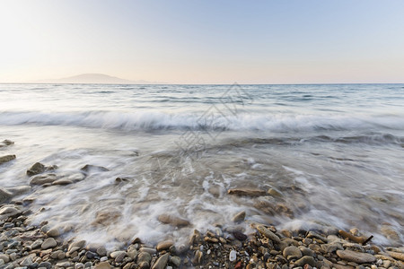 日出橙假期落时在希腊Zakynthos的石滩上海浪图片