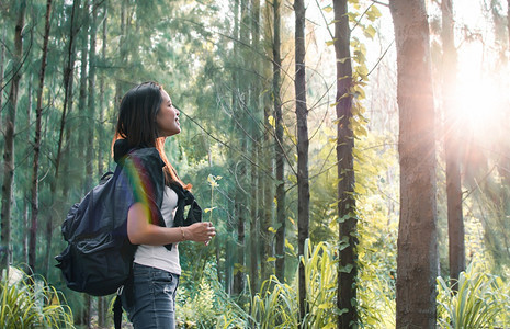 带着背包微笑的女人旅行在森林露营图片