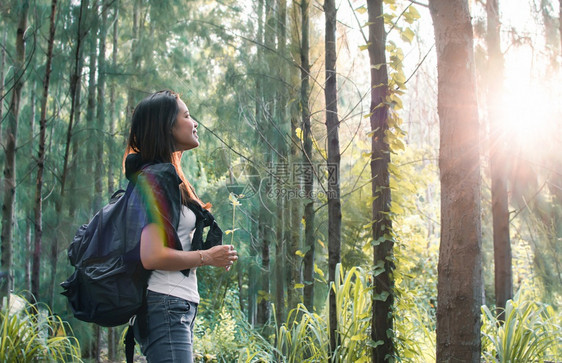 带着背包微笑的女人旅行在森林露营图片