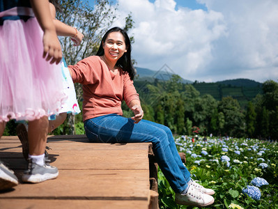 假期地面快乐的母亲与女儿坐在木地板上树有山地背景在夏日蓝天下新鲜的图片