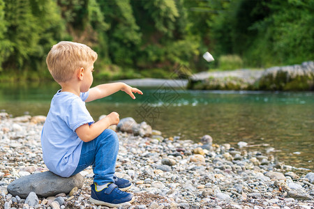 在河岸边扔石头的小男孩图片