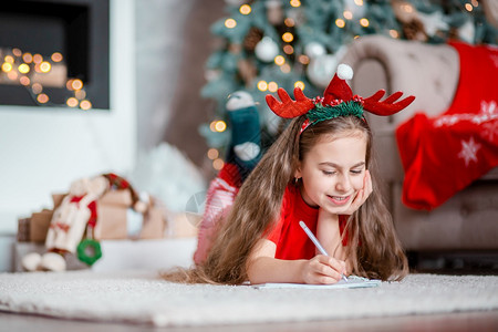 头戴着圣诞装饰的可爱女孩写信图片