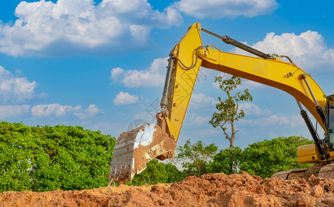 在职的土地Bucketofbackhoe正在挖掘土壤Crawler挖土机在壤中挖掘机械式地球移动器挖掘车a采掘天空图片