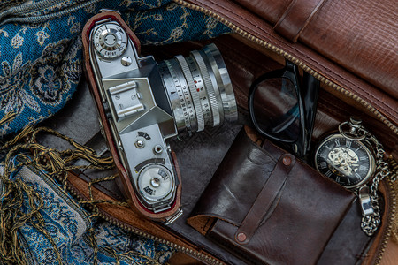 电影古老的摄相机和棕色皮包上面有围巾眼镜和袋布背景口手表的棕色皮假日旅行概念设计配件回忆图片