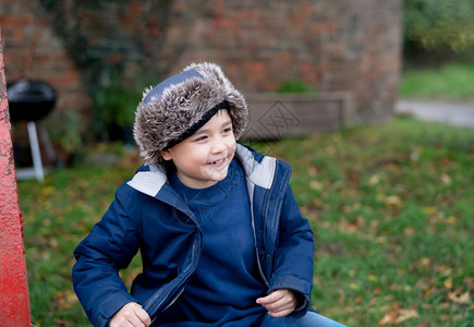 幸福快乐的男孩穿着温暖衣服坐在秋天公园肖像可爱的男孩在秋季玩户外游戏时得开心Candid拍摄了快乐的孩子用微笑脸看着外面随意的年图片