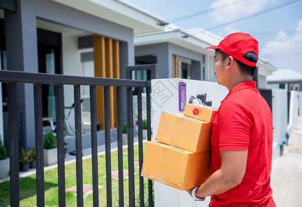 军人帽子递送工作感情亚洲货服务人员身穿红色制服有帽子并搬运纸板盒在家中门前交给女顾客在线购物和快递公司妇女背景