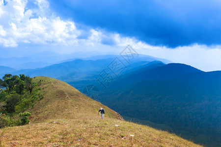 在山峰上徒步登神奇的蓝云和山地背景中的丘上一位高男子退休寂寞健康图片