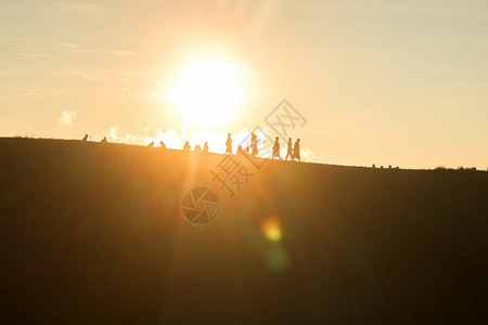 背部旅行者们在山上面对日落的橙色光照耀着太阳女孩光图片