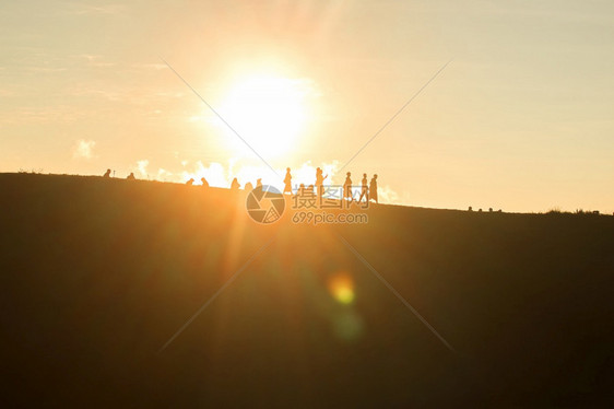 背部旅行者们在山上面对日落的橙色光照耀着太阳女孩光图片
