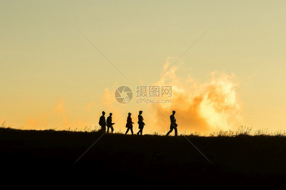 树商业两极旅行者们在山上面对日落的橙色光照耀着太阳图片