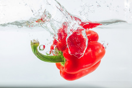 降低营养甜辣椒在水中喷洒红辣椒在白色背景的面上加红甜辣椒是一种不品尝背景图片
