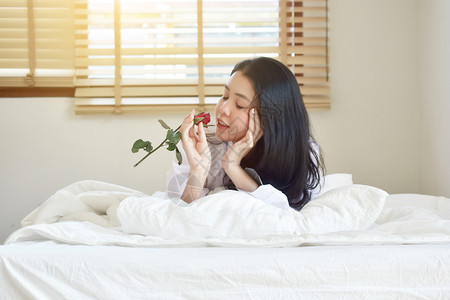 穿着白衬衫手拿鲜花躺在床上的美女图片