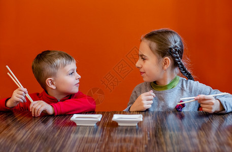 桌子真希小女孩在餐馆吃寿司孩子们在餐馆等食物小姑娘在餐厅吃寿司小女儿在餐馆吃寿司鱼图片