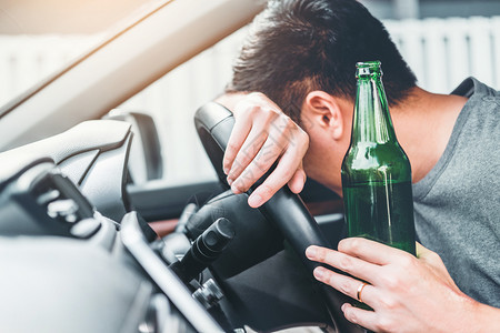 醉酒男子驾驶一辆汽车在路上载着啤酒瓶的车危险醉酒驾驶概念保持鬼运输图片