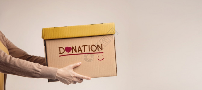 人们以捐赠标签微笑和心站立反对Walll侧面观点的捐赠概念女装有捐赠物品盒服务人图片