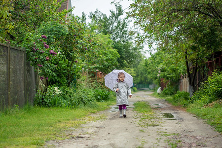 村庄城市夏天走在雨中的小女孩打着雨伞水坑夏天走在雨中的小女孩打着雨伞夹克图片