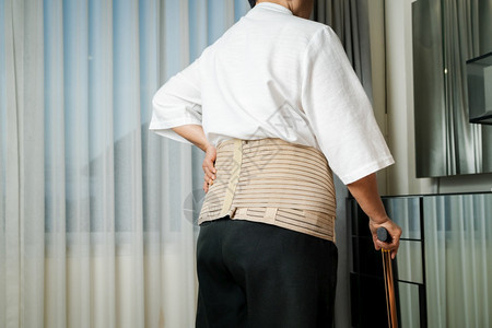 医生在家用手杖走路的老年后背疼痛妇女沮丧步行图片